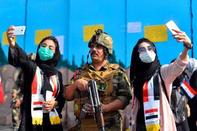 Iraqi students take selfies with a member of the Iraqi security forces during ongoing anti-government protests in the central city of Diwaniyah on 31 October 2019. Photo: Getty Images.