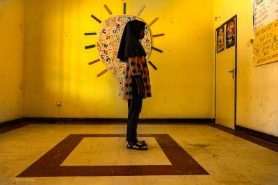 A girl stands in silhouette in front of a mural in a yellow room