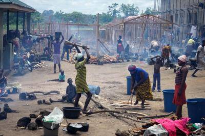 Women chop wood to build structures in a refugee camp