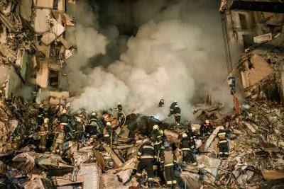 Rescue workers scrabble in the ruins of a smouldering building hit by Russian fire in Dnipro, Ukraine, 14 January 2023