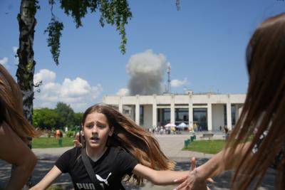 A child and a woman flee an explosion caused by a missile strike behind the Palace of Culture in Pervomaiskyi, Ukraine, 4 July 2023