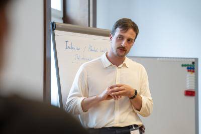 man in white shirt stands in front of flip chart