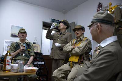 men in Japanese imperial army uniforms sit down to have a drink