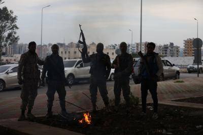 men stand around a fire holding guns