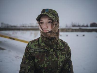 young women in army uniform stands in snowy field
