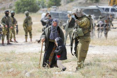 woman with a young child is forced to move by a soldier