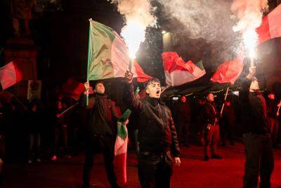 young man holding an Italian flag marches at rally 