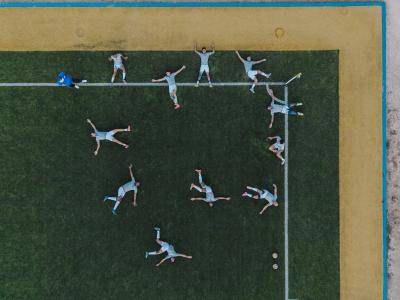 birds-eye view of football players stretching on a pitch