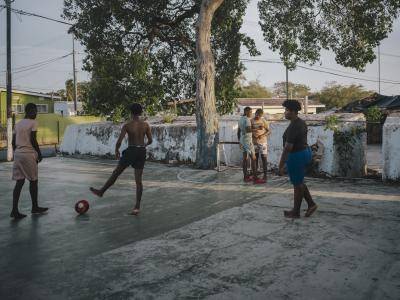 young boys kick a football around on a concrete pitch