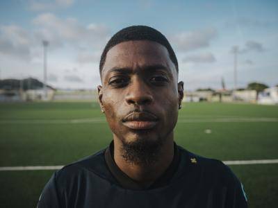 close up of a young man standing in front of football pitch