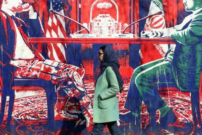 a woman in a head scarf walks past a mural