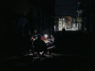 Men sit in dark street playing card with headtorches on