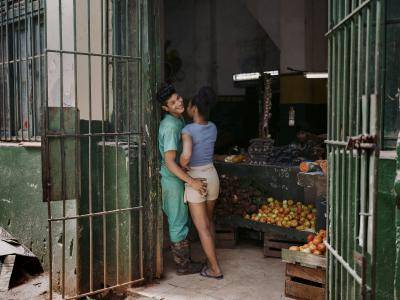 A young man embraces his girlfriend in the entrance to a fruit market