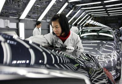 Workers operate on the assembly line at the new Dongfeng Citroen factory in Wuhan, Hubei Province, China on 24 November 2009
