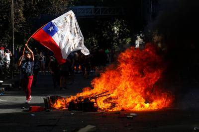 A demonstrator waves a Chilean flag during a protest in Santiago on 21 October 2019. Photo: Getty Images.