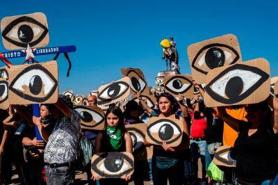 Demonstrators hold placards depicting eyes – in reference to police pellets hitting demonstrators' eyes – during a protest in Santiago on 10 December 2019. Photo: Getty Images.
