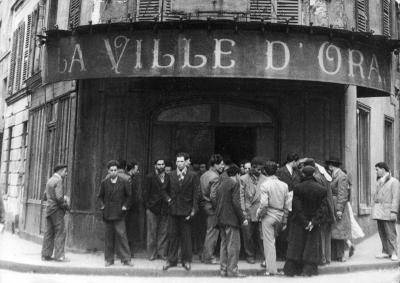 In Paris in April 1950, North African immigrants talk in front of a hotel named La Ville D'Oran (The City of Oran) w</body></html>