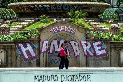  A couple walks by graffitis reading "We Are Hungry" and "Maduro Dictator" in Caracas on August 8, 2017.
