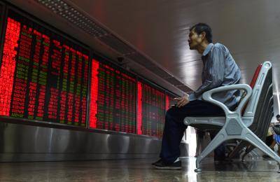 An investor looks at a board showing stock market movements at a securities company in Beijing on 10 July 2015. Photo by Getty Images.