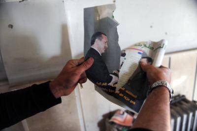 A Syrian rebel fighter tears a picture of Recep Tayyip Erdoğan, the Turkish Prime Minister, shaking hands with Syria's Assad. Photo: Bulent Kilic/AFP/Getty Images