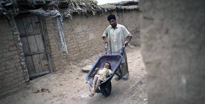 Jamshid, an 8-year-old polio sufferer, is wheeled through the back streets of Islamabad. Photo: AFP/Getty Images