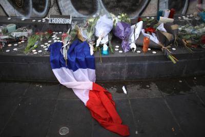 A French tricolour and flowers are placed in tribute at Place de la Republique in Paris. Photo by Getty Images.