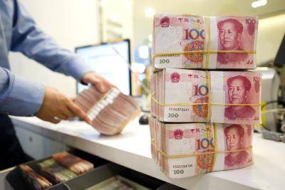 An employee stacks bank notes in a Standard Chartered branch in Shanghai. Photo by Getty Images.