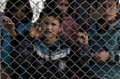 Migrant children stand behind a fence at the Moria reception centre in Mytilene on 23 February 2016. Photo by Getty Images.