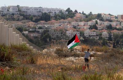 A man waves a Palestinian flag following a protest against settlements in Ramallah on 19 September 2014. Photo by Getty Images.
