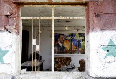 A poster of Bashar al-Assad in an apartment block damaged in a car bomb attack near Sayyida Zeinab. Photo by Getty Images.