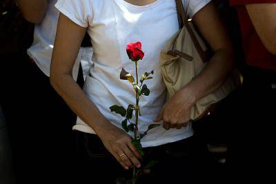A supporter of former Thai prime minister Yingluck Shinawatra holds a rose as she awaits her arrival at a local polling station during the constitutional referendum in Bangkok. Photo by Getty Images.