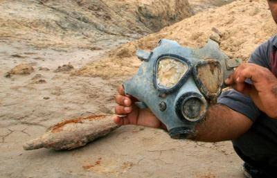 An Iraqi carries a gas mask that he found in the marshes crossing the southern Iraqi town of al-Azeir, April 2007. Photo: Getty Images.