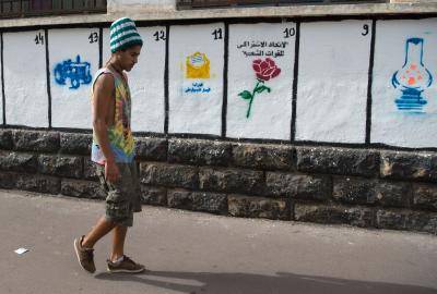 A Moroccan youth walks past a wall depicting the symbols of the political parties running for the parliamentary elections in Morocco on 7 October 2016. Photo by Getty Images.