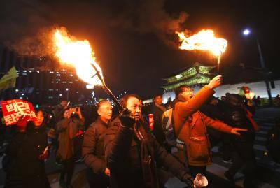 South Korean protesters hold torches during a rally against the president in central Seoul. Photo by Getty Images.