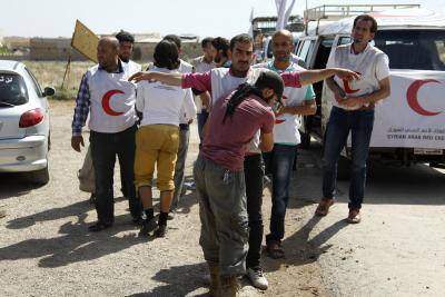 A rebel fighter searches Syrian Arab Red Crescent members before they are sent to deliver food aid to Aleppo Central Prison, 11 May 2014. Photo: Ammar Abdullah/Reuters/Corbis.