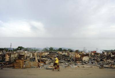 A woman walks past destroyed stalls at Kafanchan central market on 25 April 2011 in Kaduna. Photo: Getty Images.