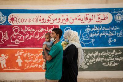 Syrians walk past a mural painted as part of an awareness campaign by UNICEF and WHO, bearing instructions on protection from COVID-19, in the Kurdish-majority city of Qamishli, Syria, on 16 August 2020. Photo by Delil Souleiman/AFP via Getty Images.