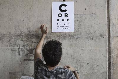 An anti-government protester in Beirut puts up a poster accusing corruption in Lebanon's state judiciary. Photo by Sam Tarling/Getty Images.
