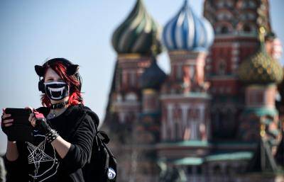 Young woman wearing a face mask in front of St. Basil's Cathedral, Moscow. Photo by ALEXANDER NEMENOV/AFP via Getty Images.