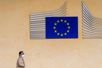 A pedestrian wearing a protective face mask passes a sign showing the stars of the European Union outside the Berlaymont building, which houses offices of the European Commission, in Brussels, Belgium, on 8 June 2020. Photo: Geert Vanden Wijngaert/Bloomberg via Getty Images.