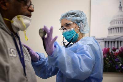 Examining a patient while testing for COVID-19 at the Velocity Urgent Care in Woodbridge, Virginia. Photo by Chip Somodevilla/Getty Images.