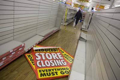 Empty shelves and shop fittings, sheets of closing down posters lying on the shop floor. Photo by In Pictures Ltd./Corbis via Getty Images.