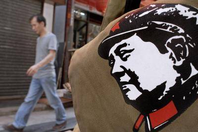 A man walks past a bag printed with the portrait of China's revolutionary leader Mao Tse-tung on display outside a shop in Hong Kong. Photo by PHILIPPE LOPEZ/AFP via Getty Images.