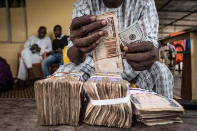 A currency dealer counts bundles of naira banknotes for exchange on the 'black market' in Lagos, Nigeria. Photographer: Tom Saater/Bloomberg via Getty Images.