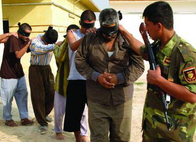 An Iraqi soldier leads detainees held in Baqouba 