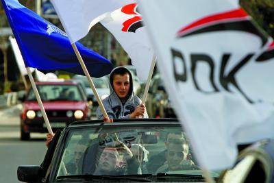 Supporters of the Democratic Party of Kosovo wave party flags.</body></html>