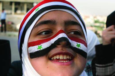 A Syrian child has the Syrian flag painted on his face.</body></html>